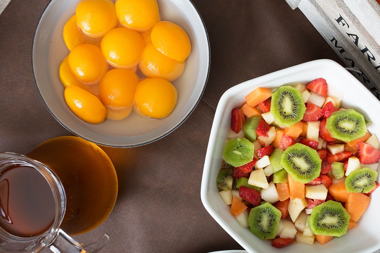 Un bol con frutas cortadas y una taza de té sobre una mesa.