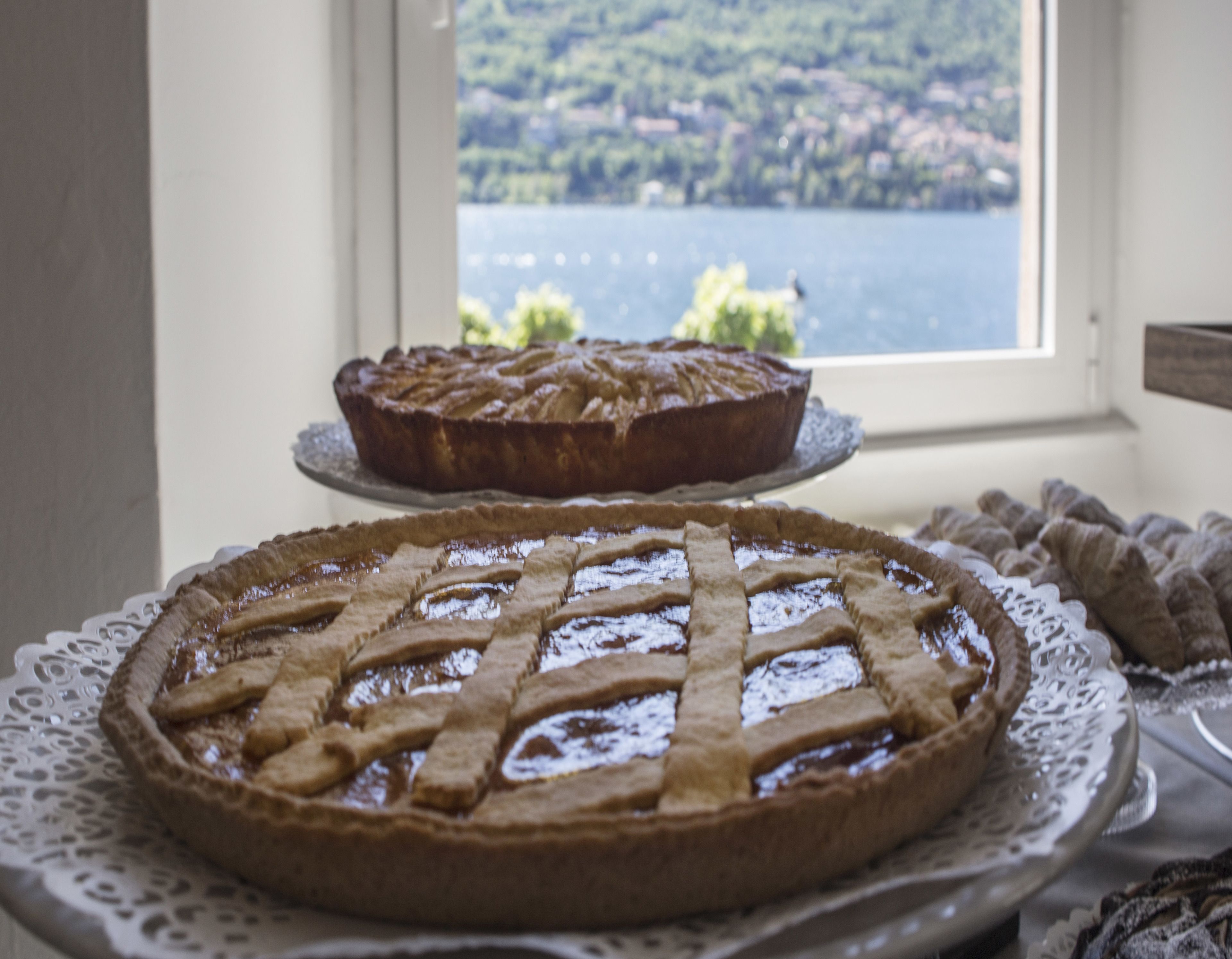 Deux tartes, présentées sur des sets de table blancs, avec une vue sur un lac et des collines par la fenêtre.
