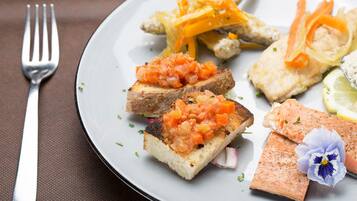 A plate with grilled salmon, avocado slices, and a small flower.