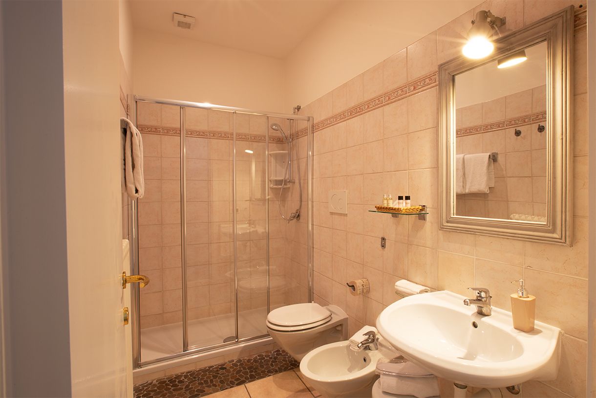 Ein Badezimmer mit einer Duschkabine, einer Toilette, einem Bidet und einem Waschbecken mit Spiegel darüber.