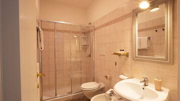 Ein Badezimmer mit einer Duschkabine, einer Toilette, einem Bidet und einem Waschbecken mit Spiegel darüber.