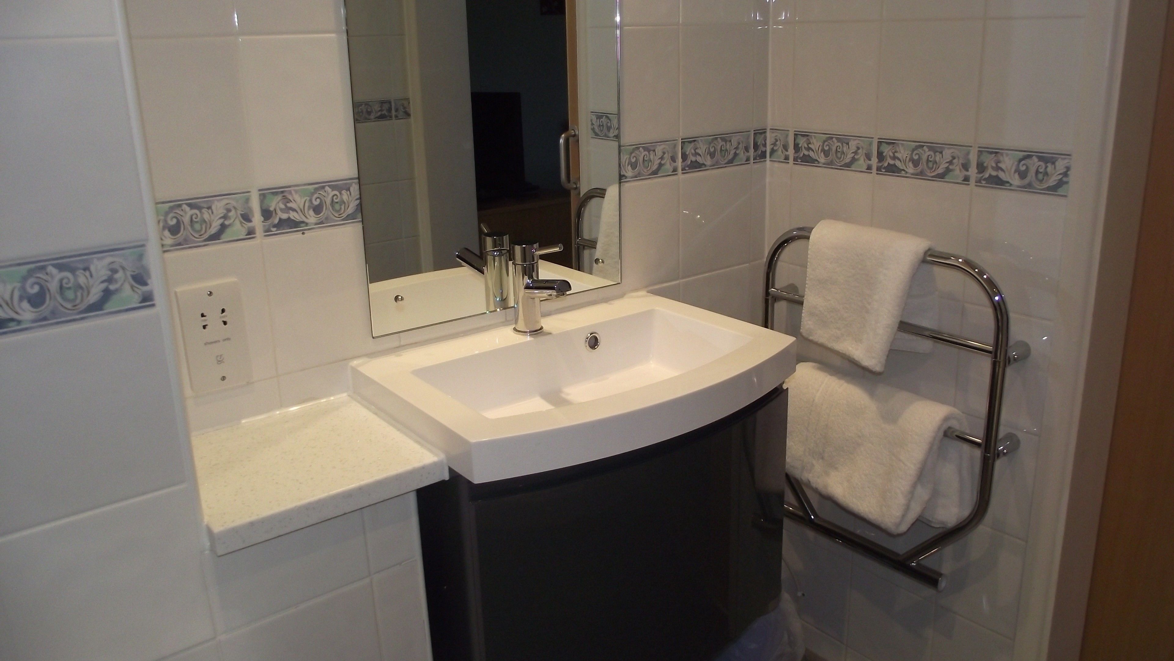 A bathroom with a white sink, a mirror, and a towel rack.