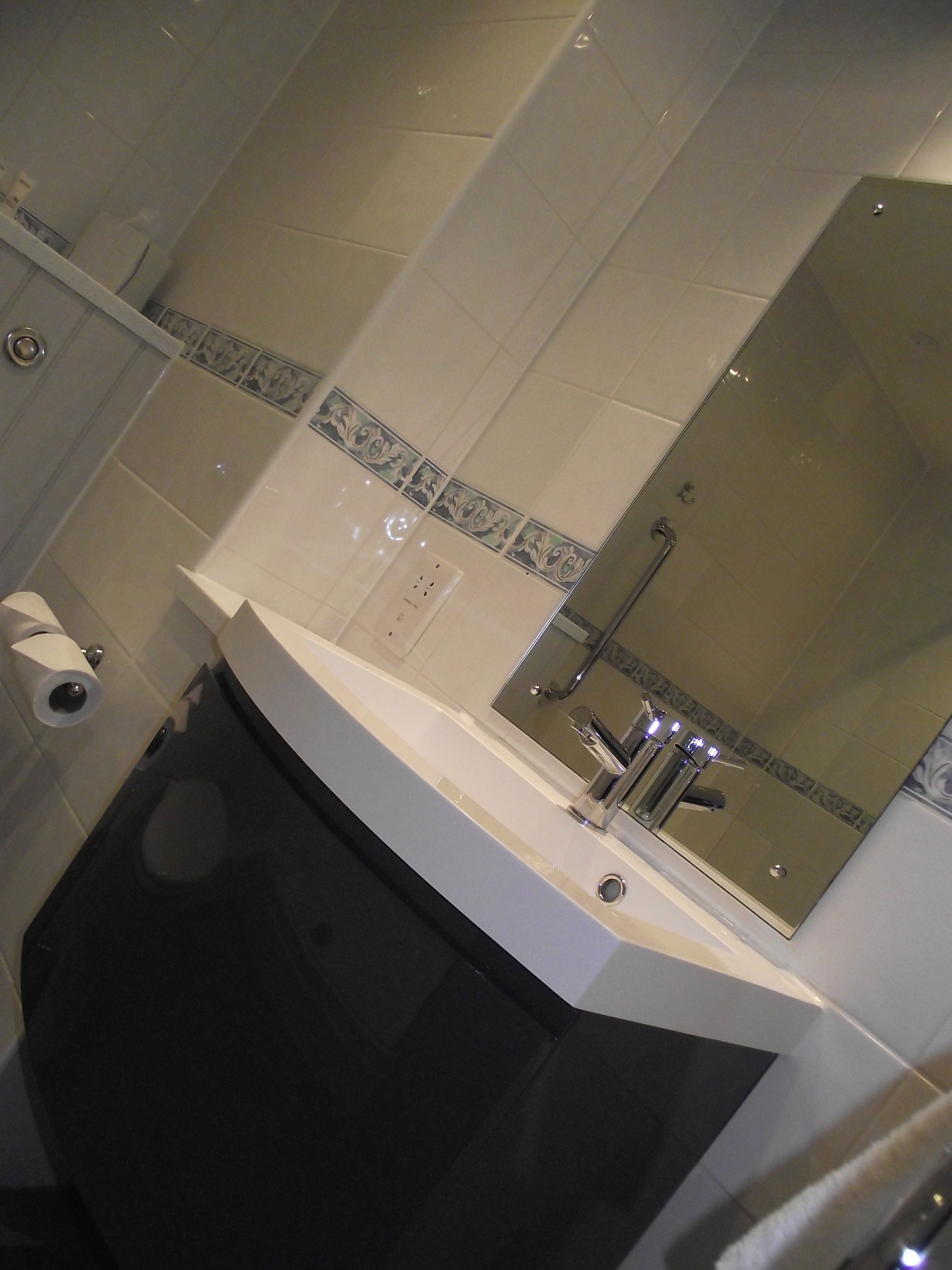 Un baño con lavamanos blanco, un espejo y un inodoro.