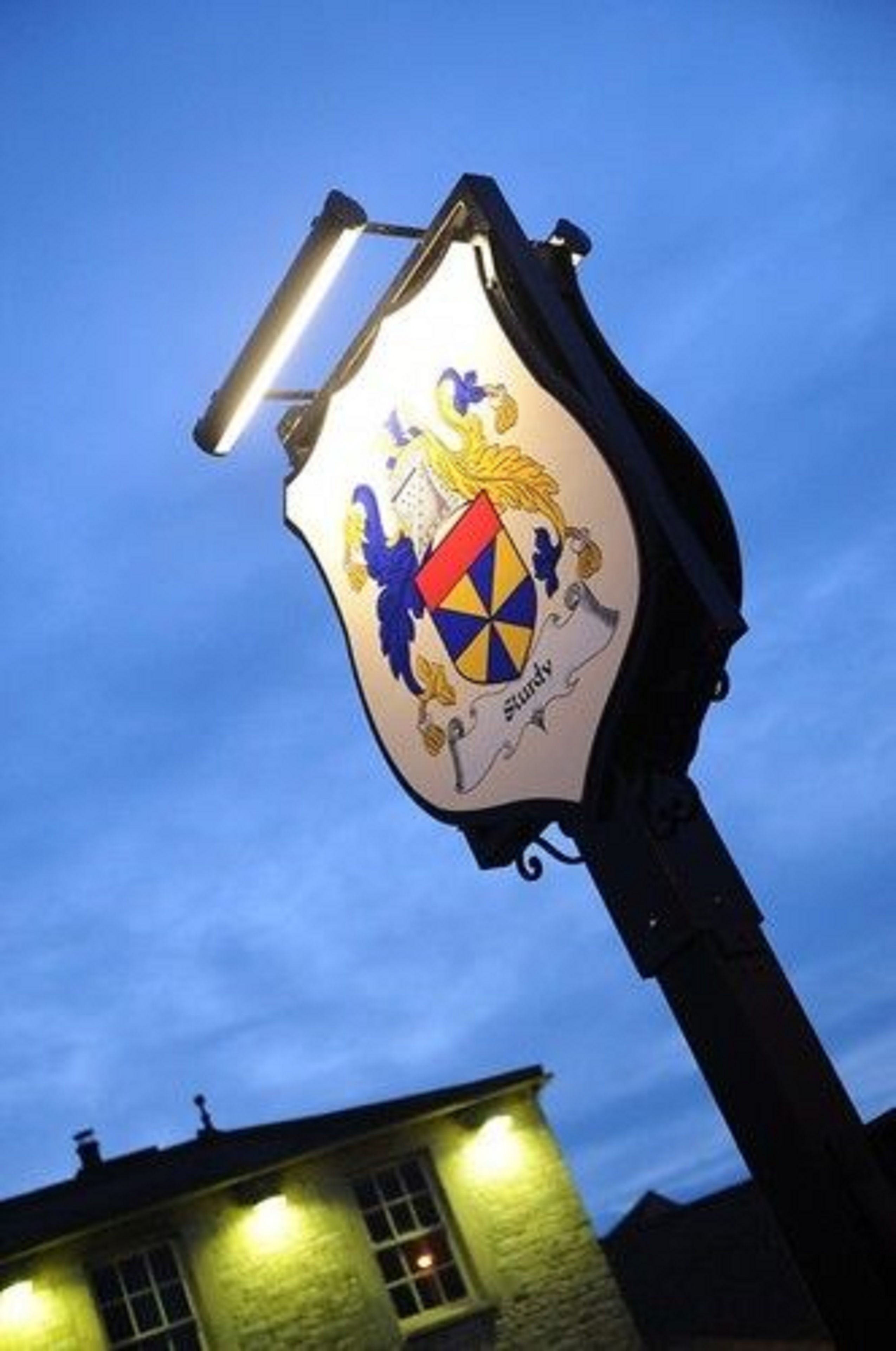 Ein Gebäude mit beleuchteter Schrifttafel und Wappen.
