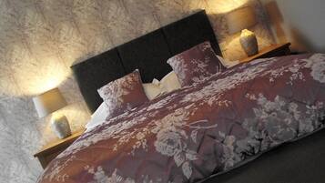 Un lit avec une couvre-lit à motifs floraux, deux lampes de chevet et une tête de lit.