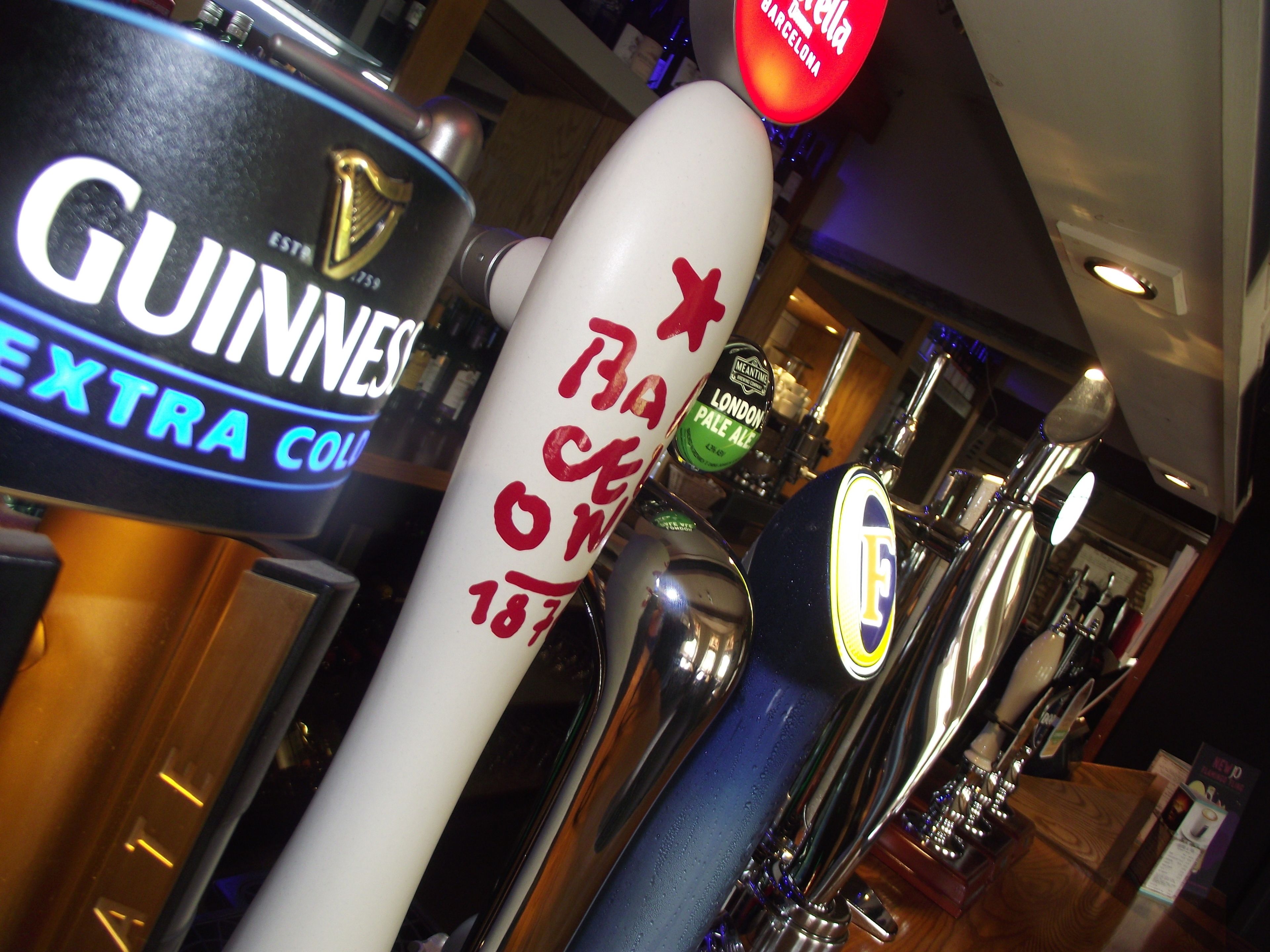 Una fila de grifos de cerveza, incluyendo Guinness y otras marcas, con un grifo destacado que dice 'Bacardi 1873'.