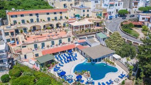 Un hotel con piscina, lettini e una terrazza coperta.