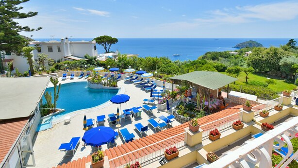 Un resort con piscina, lettini e vista sul mare.