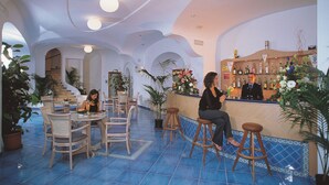 Angolo bar con sgabelli, bancone e diverse bottiglie.