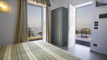 Quarto com cama, guarda-roupa e varanda com mesa e cadeiras.