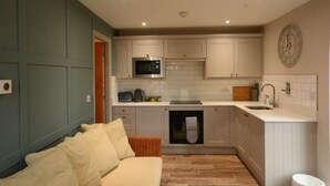 A compact kitchen with white cabinets, a microwave, and a sink. - Durham City Cottages (Durham)
