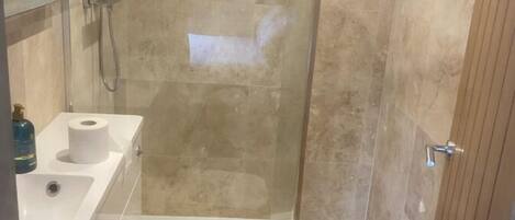 A bathroom with a glass-enclosed shower, a toilet, and a sink with a mirror.