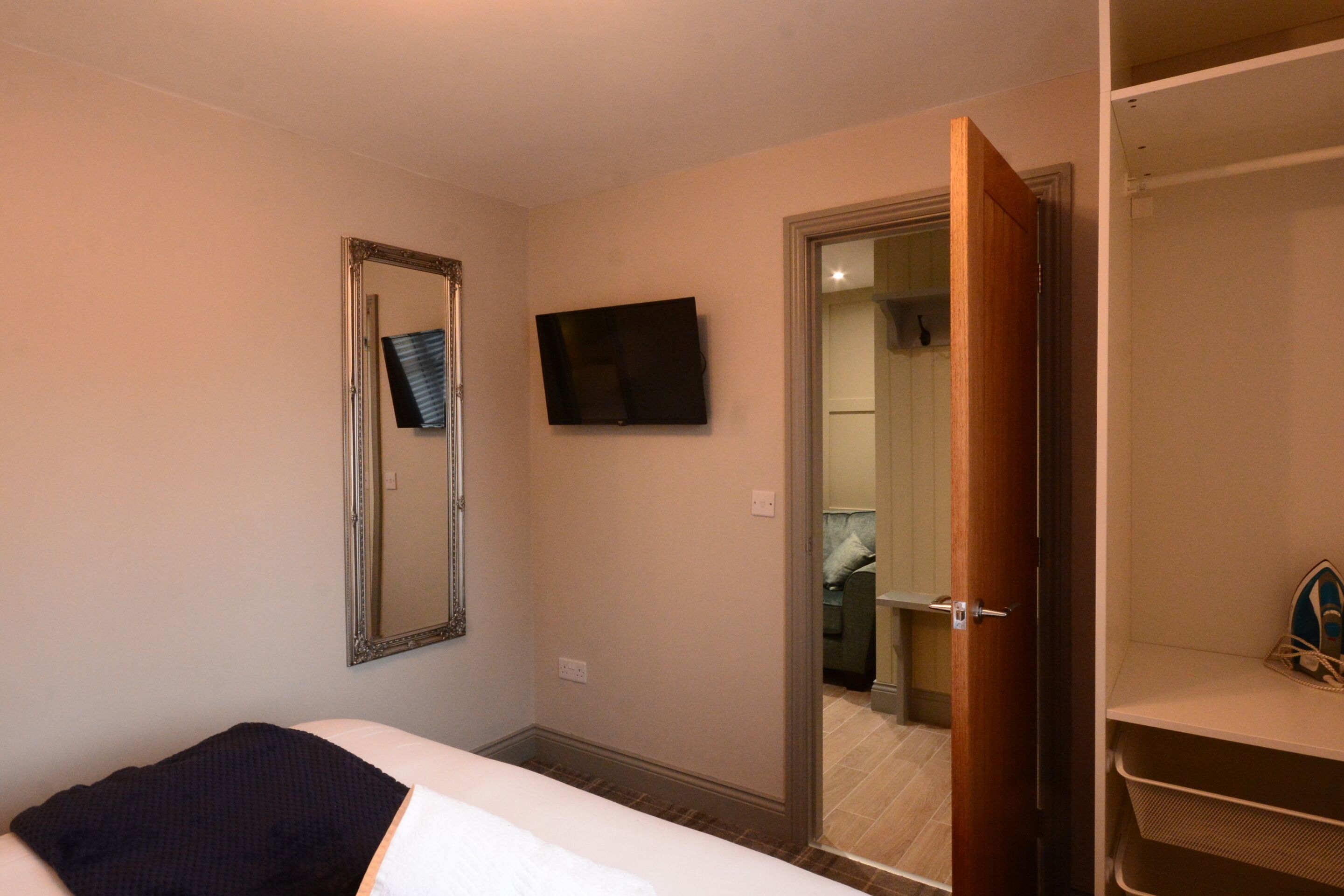 Une chambre d’hôtel équipée d’un lit, d’un téléviseur fixé au mur, d’un miroir et d’une armoire.