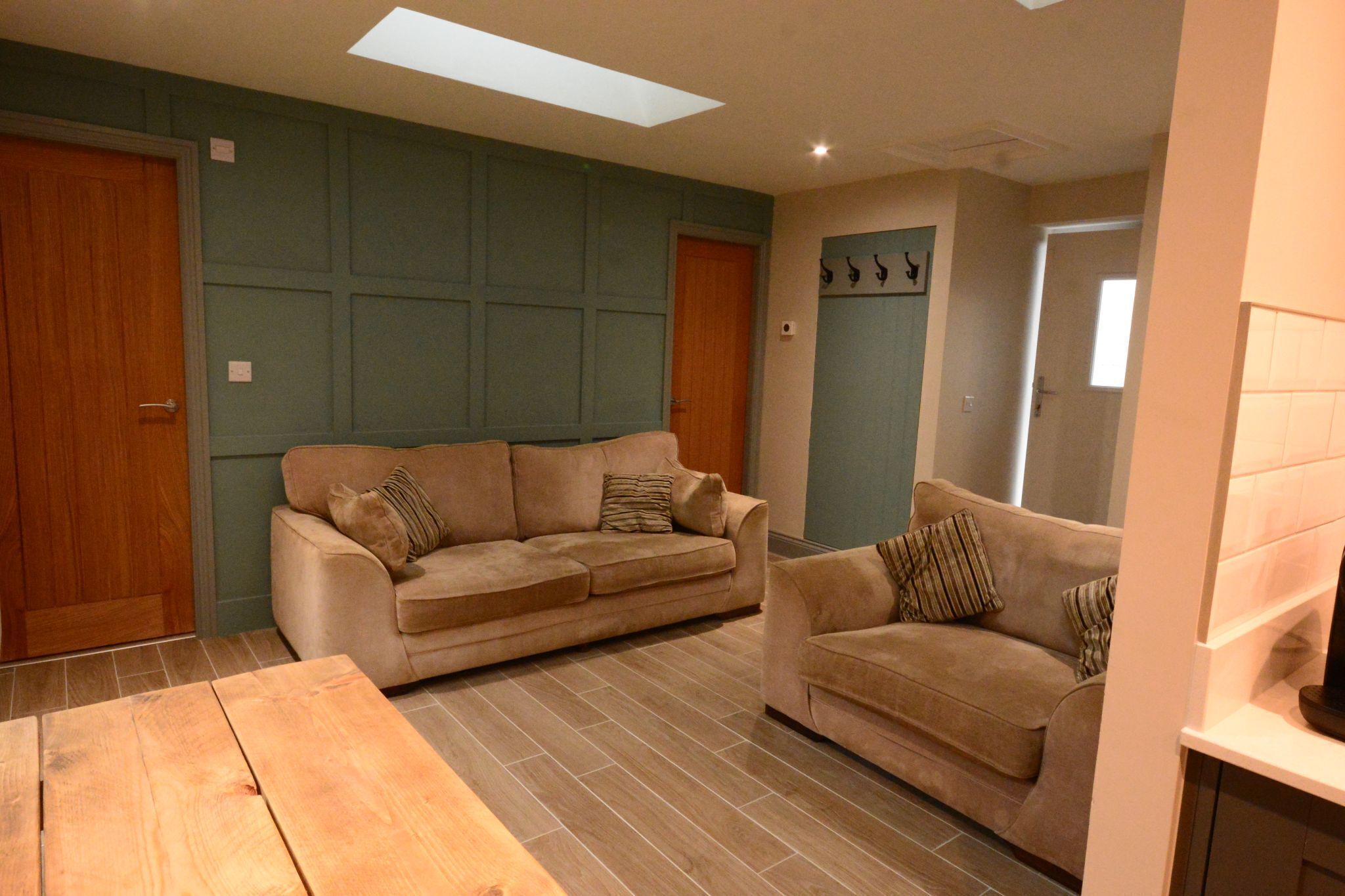 Una sala de estar con dos sofás color beige, una mesa de centro de madera y piso de baldosas.