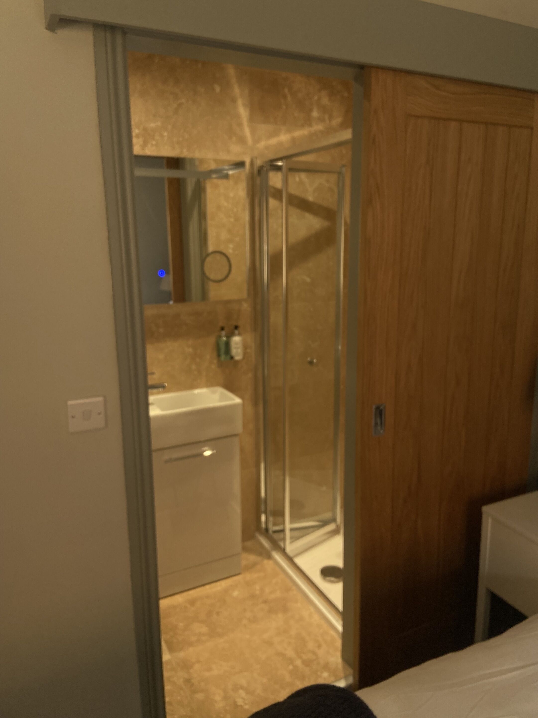 A bathroom with a glass shower enclosure, a sink, and a mirror.