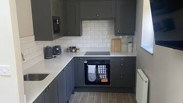 A compact kitchen with grey cabinets, a built-in oven, and a wooden table.