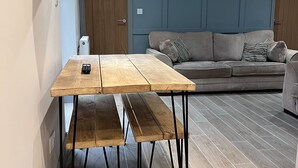A wooden table with metal legs in a room with a grey sofa and a blue wall. - Durham City Cottages (Durham)