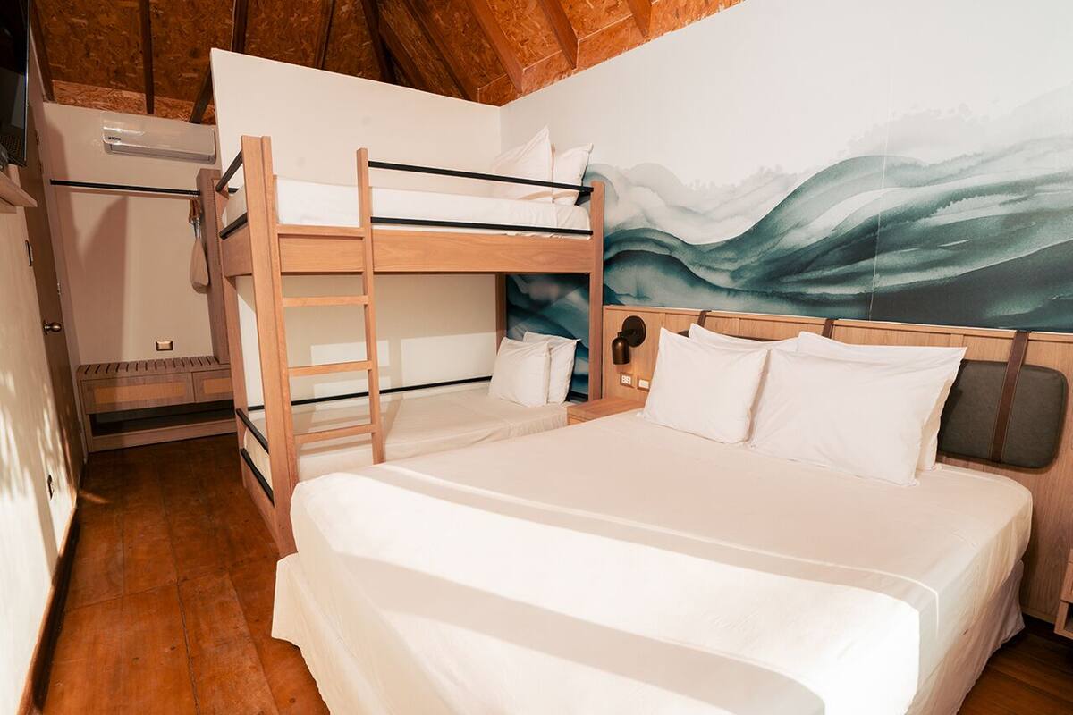Habitación con literas, techo de madera, aire acondicionado de pared y un mural de un paisaje.