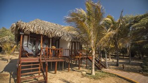 A wooden structure with a thatched roof, a wooden staircase, and a palm tree.