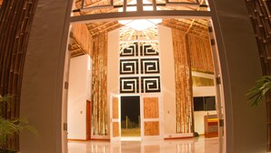 A modern hotel lobby with a geometric wall design, bamboo decor, and a polished floor.