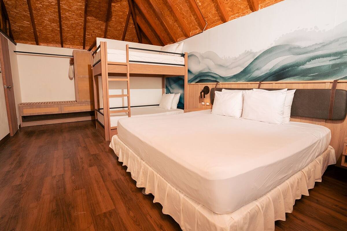 Un dormitorio con una cama litera, una cama individual, suelo de madera y un mural en la pared.