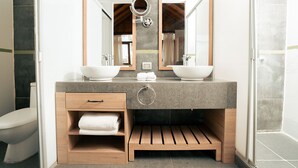 A modern bathroom with a double sink vanity, wooden shelves, and a shower area. - Aranwa Vichayito Beach Resort (Los Organos)