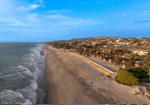 A coastal town with a beach, houses, and a hill in the background.