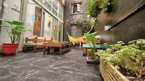 A courtyard with stone flooring, wooden benches, and potted plants. - Play Hostel Arcos (Buenos Aires)
