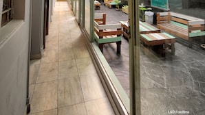 A corridor with a tiled floor, benches, and hanging plants. - Play Hostel Arcos (Buenos Aires)