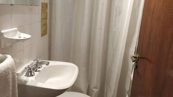Un baño con lavamanos, inodoro y cortina de ducha blancos.