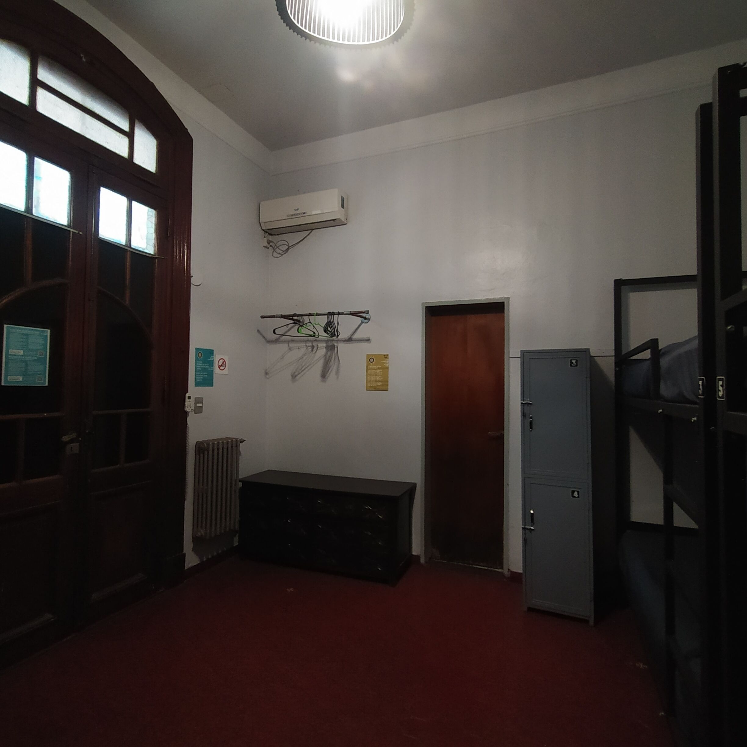 A room with a radiator, a bench, a door, and a wall-mounted air conditioning unit.