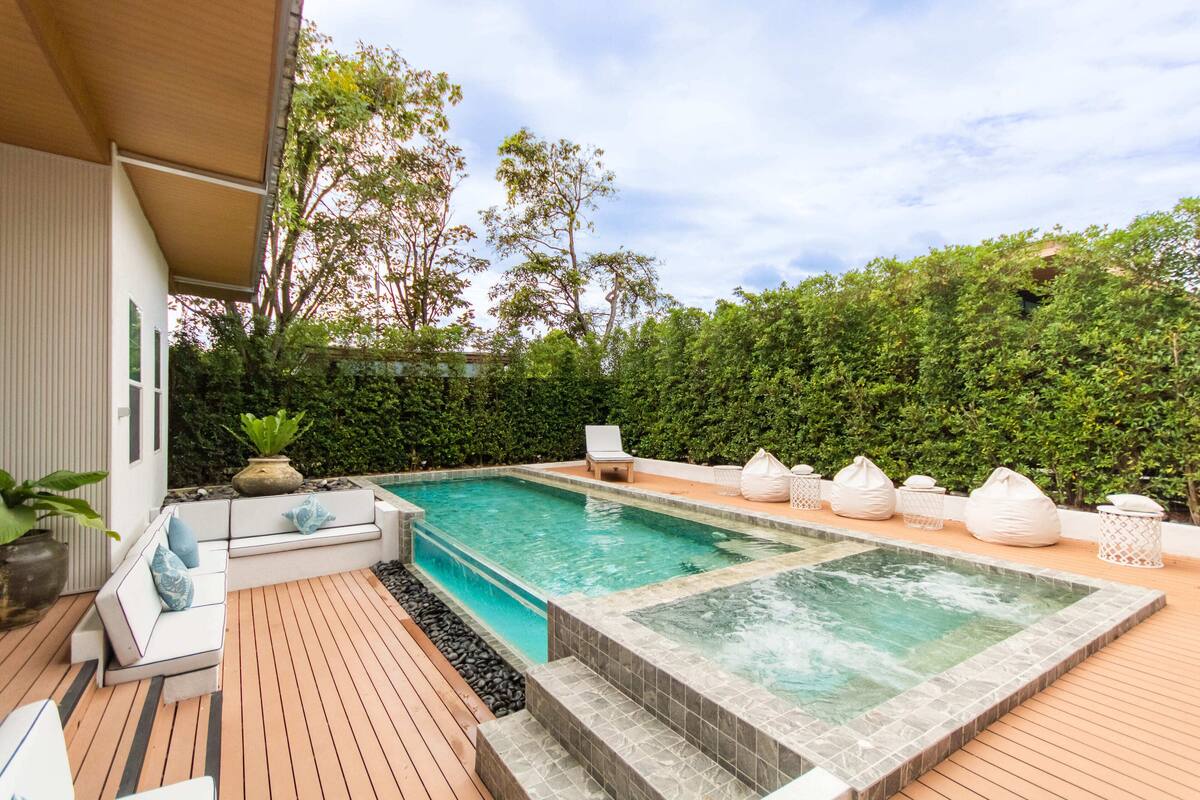 Zona de piscina con jacuzzi, asientos y terraza de madera.