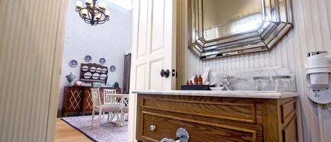 A bathroom with a wooden vanity, a large mirror, and a chandelier.