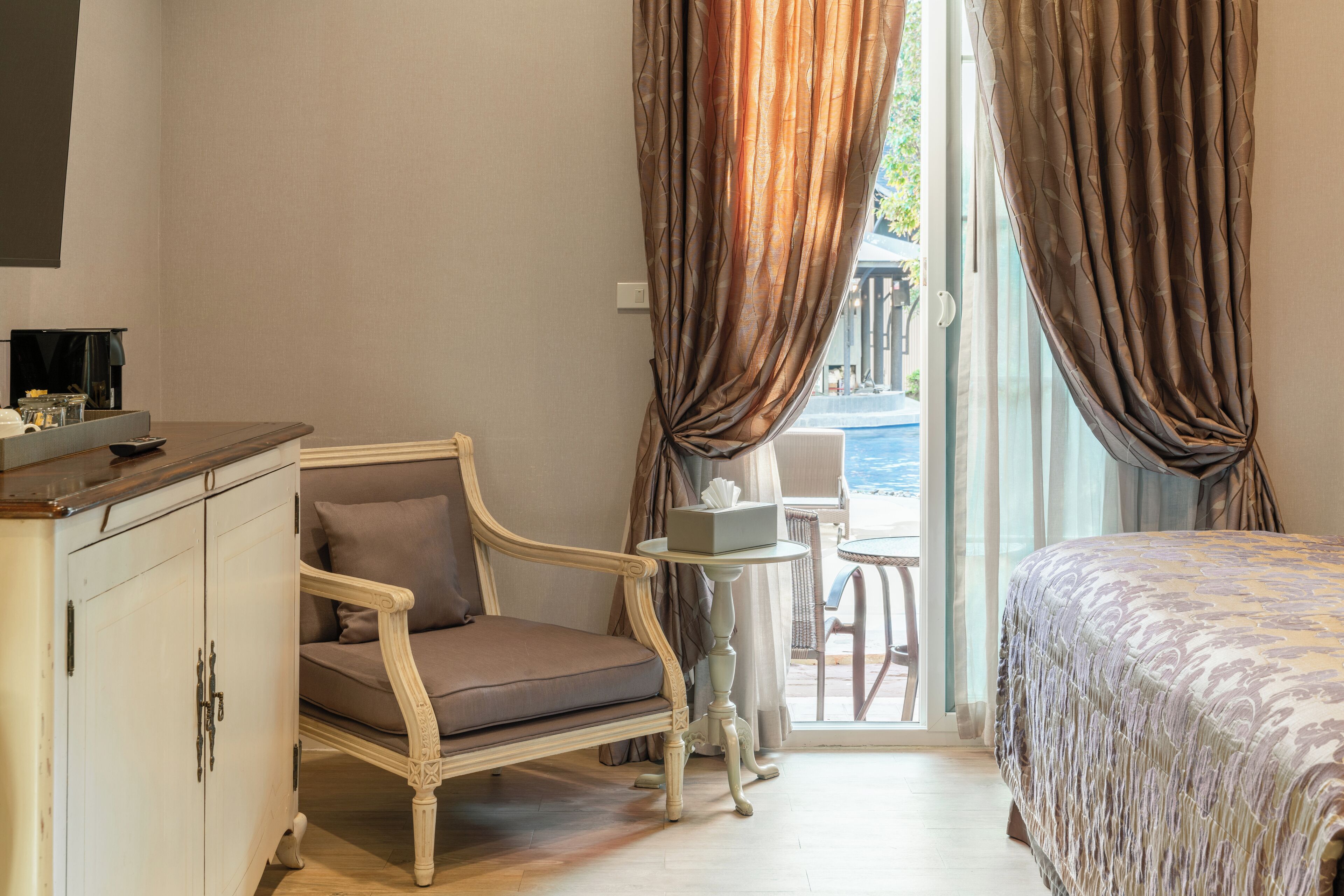 A hotel room with a bed, a chair, a small table, and a wardrobe.