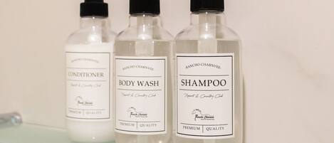 Drei Flaschen Rancho Carnvée Duschgel, Conditioner und Shampoo auf einem Glastablett.