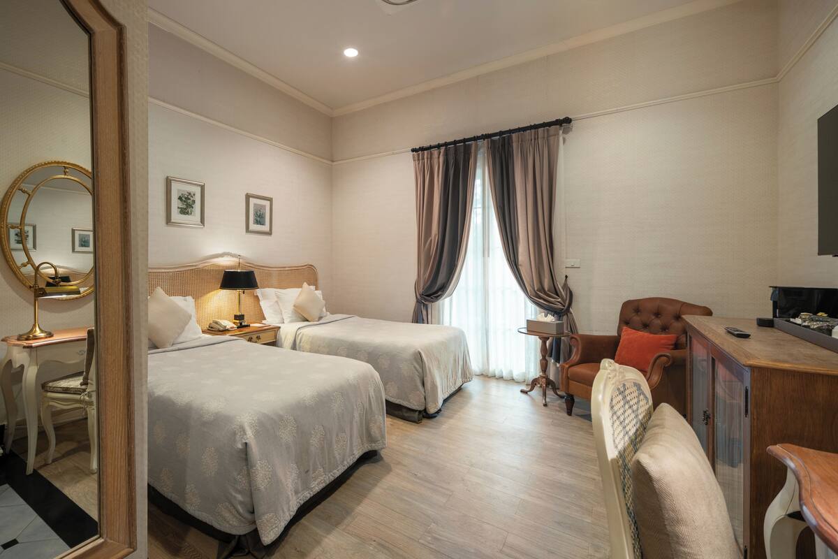 Habitación de hotel con dos camas, un escritorio, una silla, un televisor y un espejo.