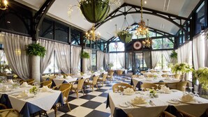 A restaurant with checkered flooring, wicker chairs, and tables set with white tablecloths and silverware. - Rancho Charnvee Khaoyai (Pak Chong)