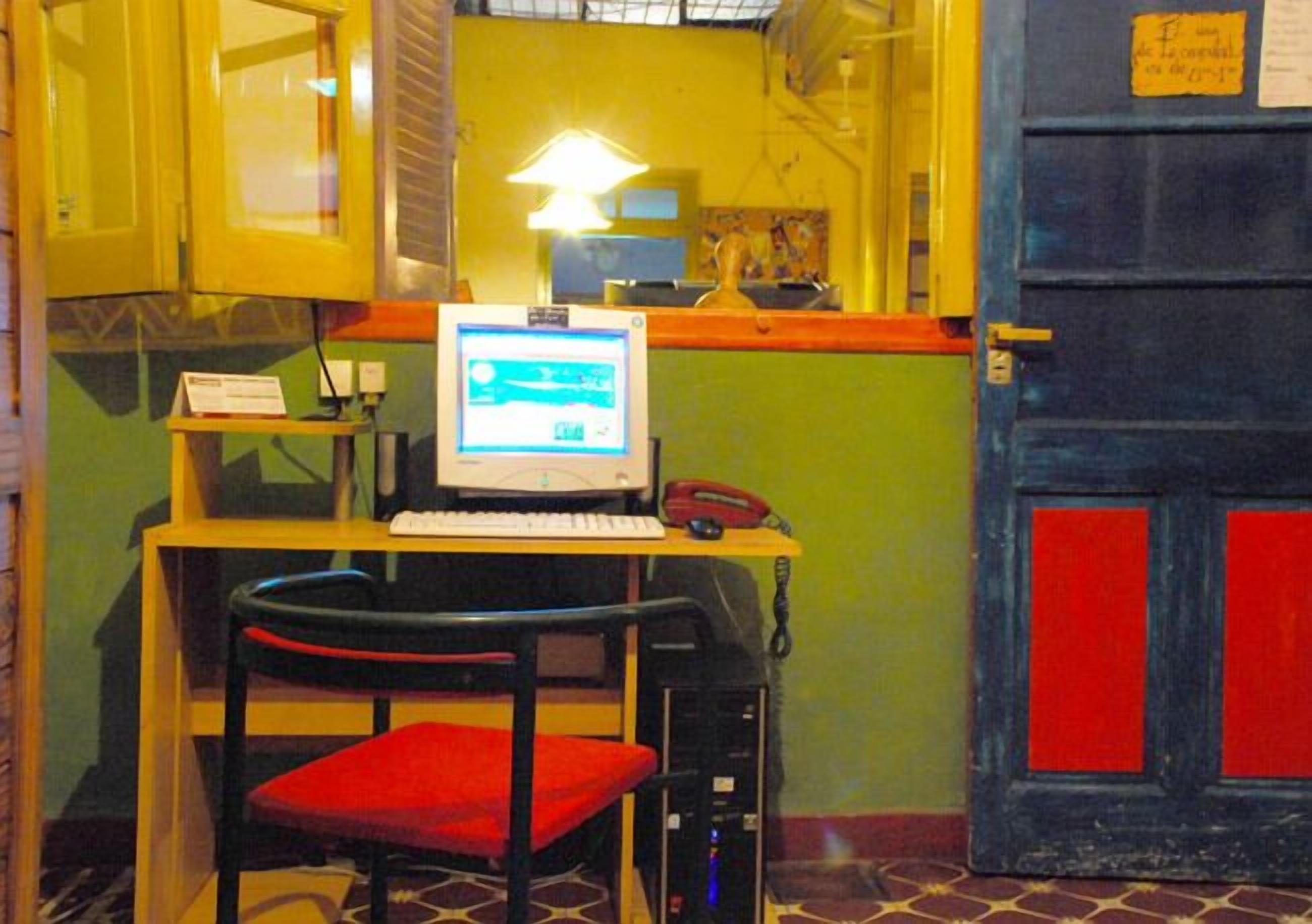 A computer desk with a monitor, keyboard, and telephone.