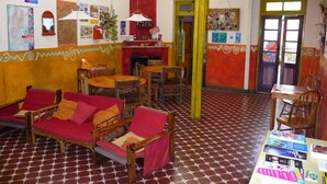 A room with a patterned floor, wooden furniture, and a table with magazines. - Casa Pueblo Hostel (Mendoza)