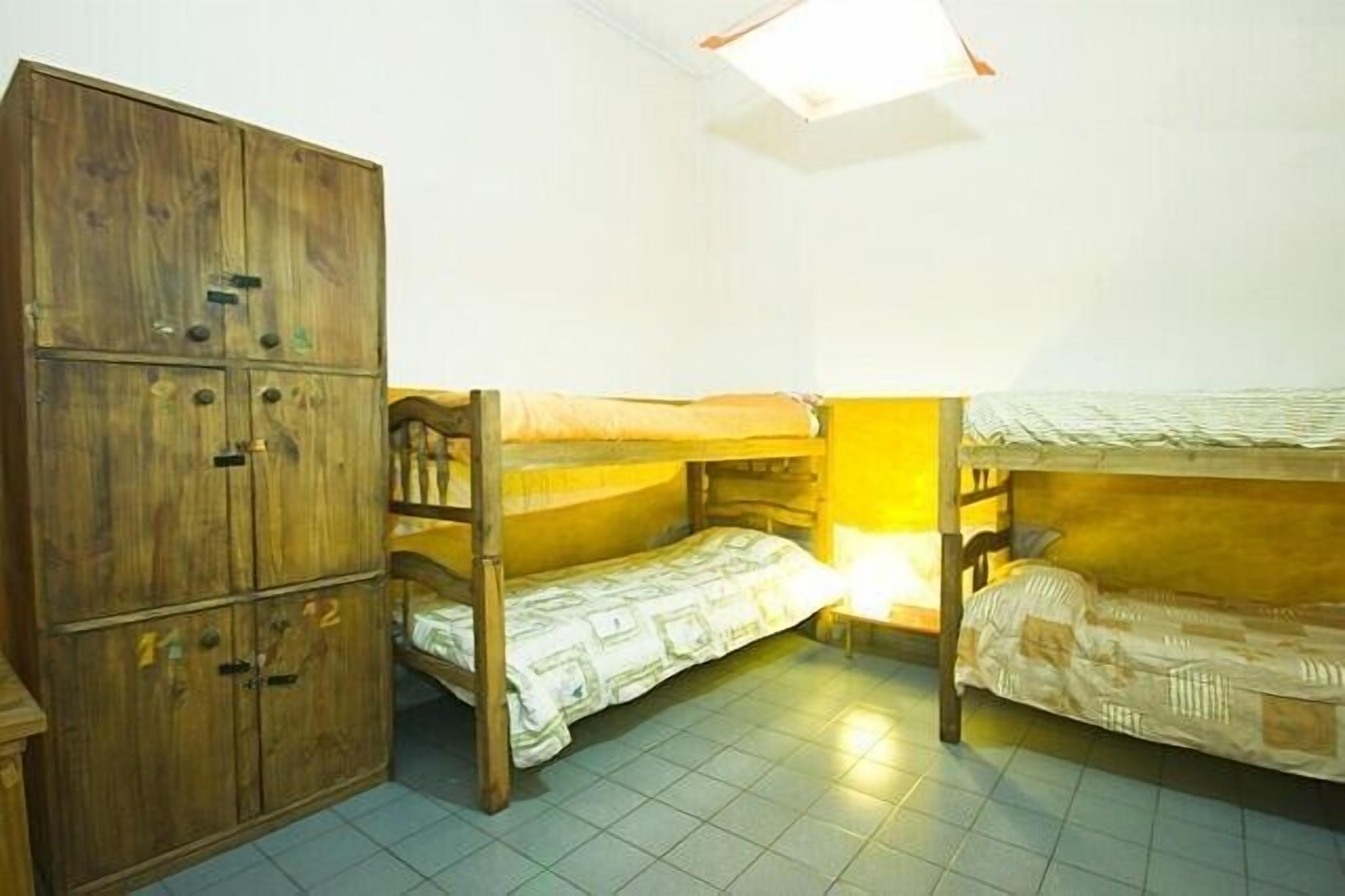 Un dormitorio con literas, un armario de madera y una lámpara en el techo.