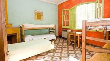 A room with bunk beds, a desk, and a window with shutters.