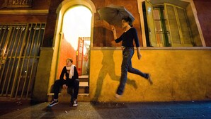 A hostel with a sign reading "CASA PUEBLO HOSTEL" and a person walking past with an umbrella. - Casa Pueblo Hostel (Mendoza)