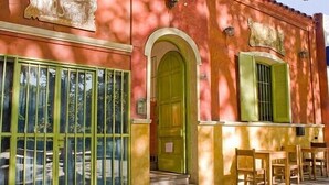 A hostel with a green door and windows, outdoor seating area, and a tiled floor. - Casa Pueblo Hostel (Mendoza)