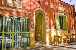 Um hostel com porta verde e janelas, área de estar externa e chão de azulejos.