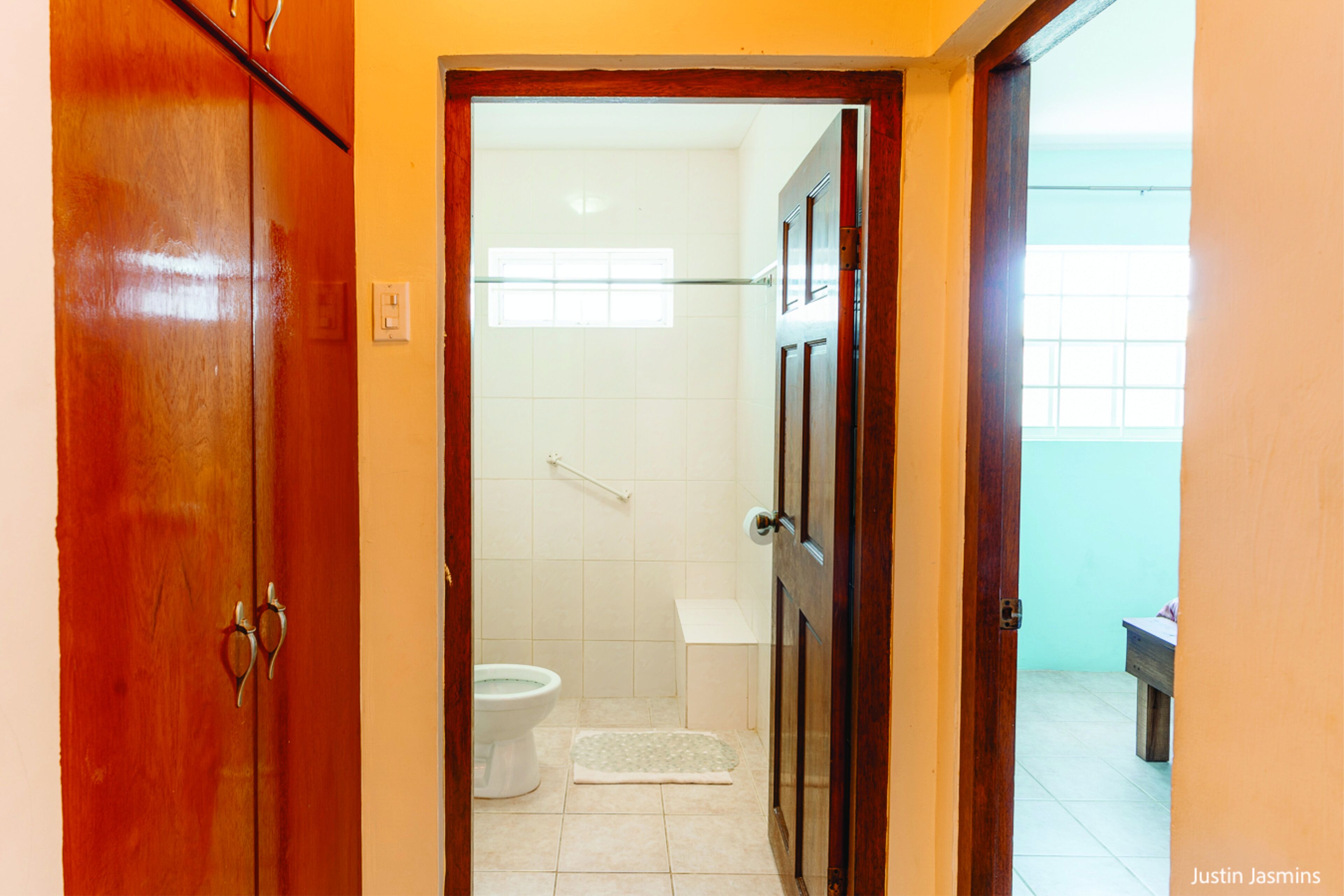 A bathroom with a toilet, a small window, and a wooden door.