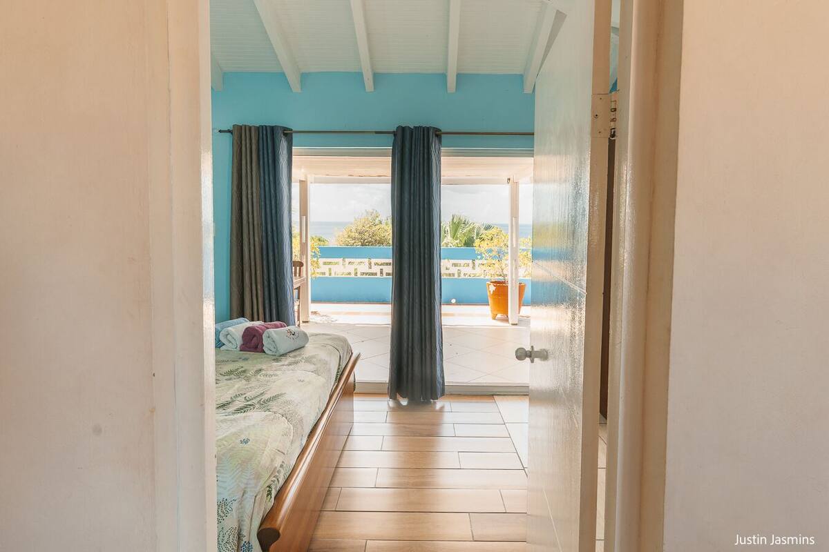 Una camera da letto con un letto, vista sul balcone e una porta che dà all'esterno.