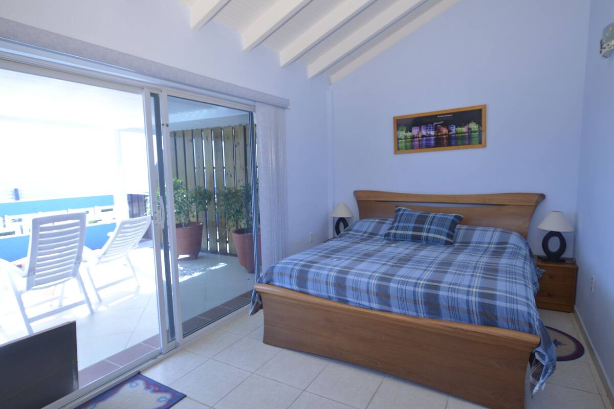 Una camera da letto con un letto, due lampade da comodino, un tavolino, una finestra vista e una pianta in vaso.
