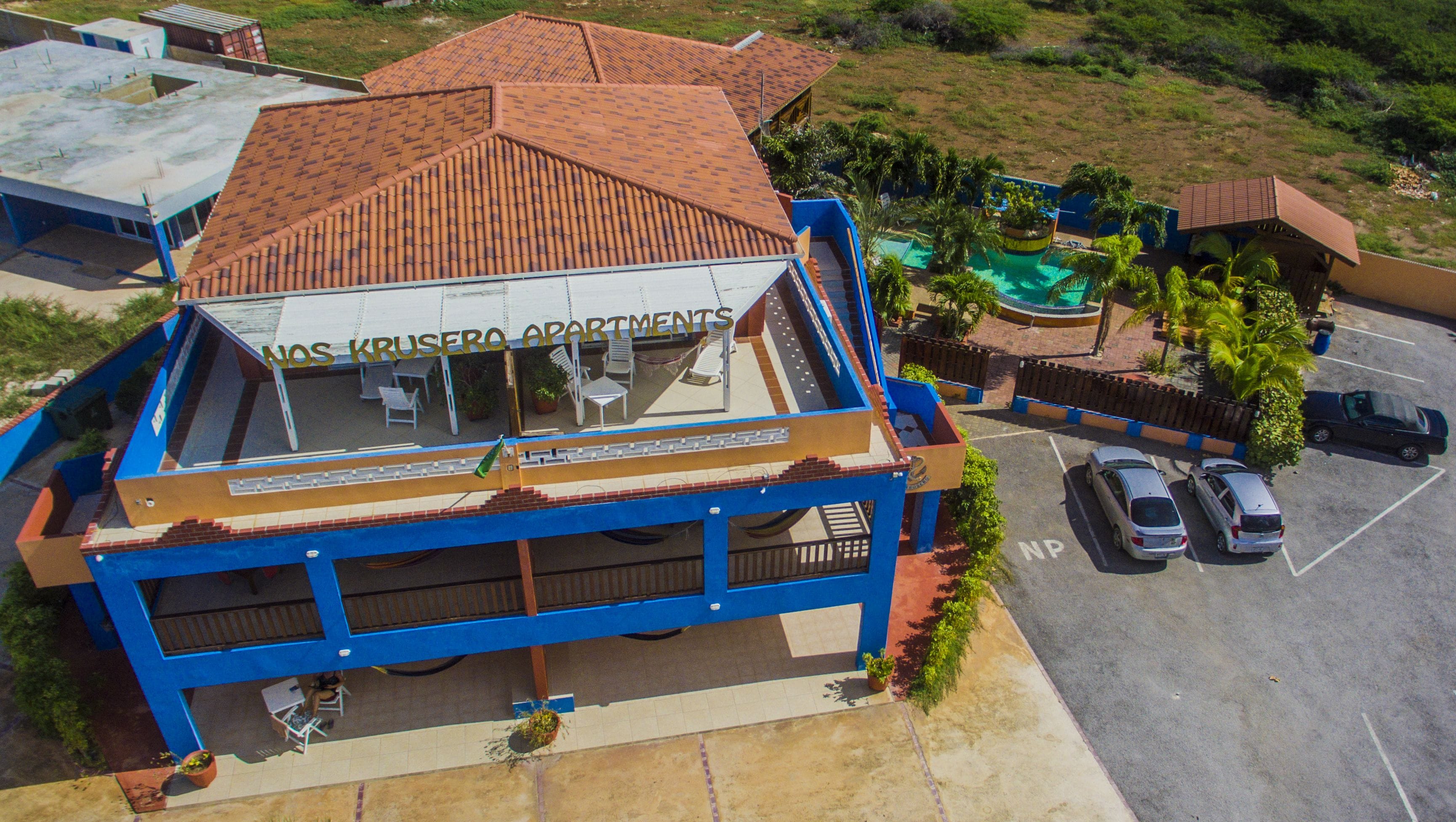 A building with a tiled roof and a sign reading "NOS CRUSERO APARTMENTS".