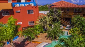 Un hotel con piscina rodeado de palmeras y un edificio de techo rojo.