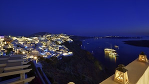 A coastal town at night with illuminated buildings and boats on the water.
